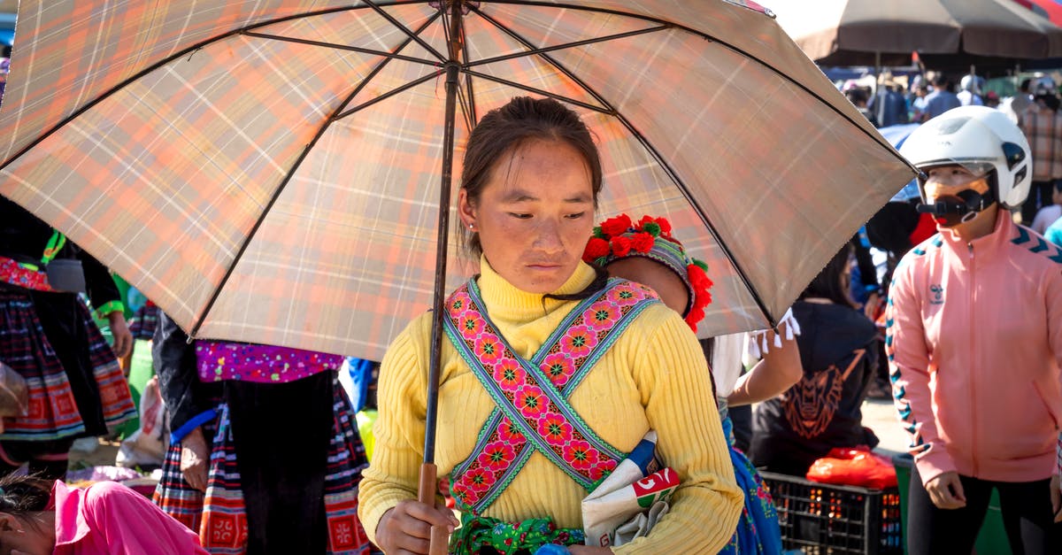 EC 261 refund: marketing vs operating carrier - Pensive ethnic mother with umbrella carrying unrecognizable toddler girl against crop people while looking down in bazaar EC 261 refund: marketing vs operating carrier - Pensive ethnic mother with umbrella carrying unrecognizable toddler girl against crop people while looking down in bazaar