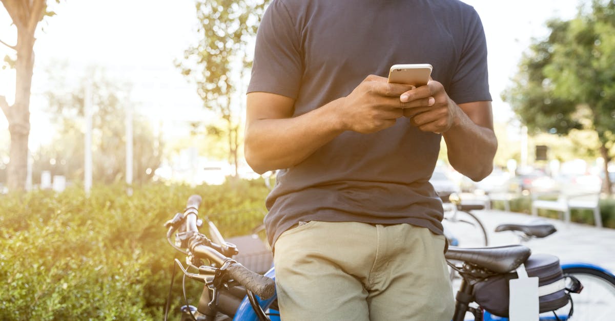 Electronic alternative to bicycle map - Person Leaning on Bike While Holding Smartphone Electronic alternative to bicycle map - Person Leaning on Bike While Holding Smartphone