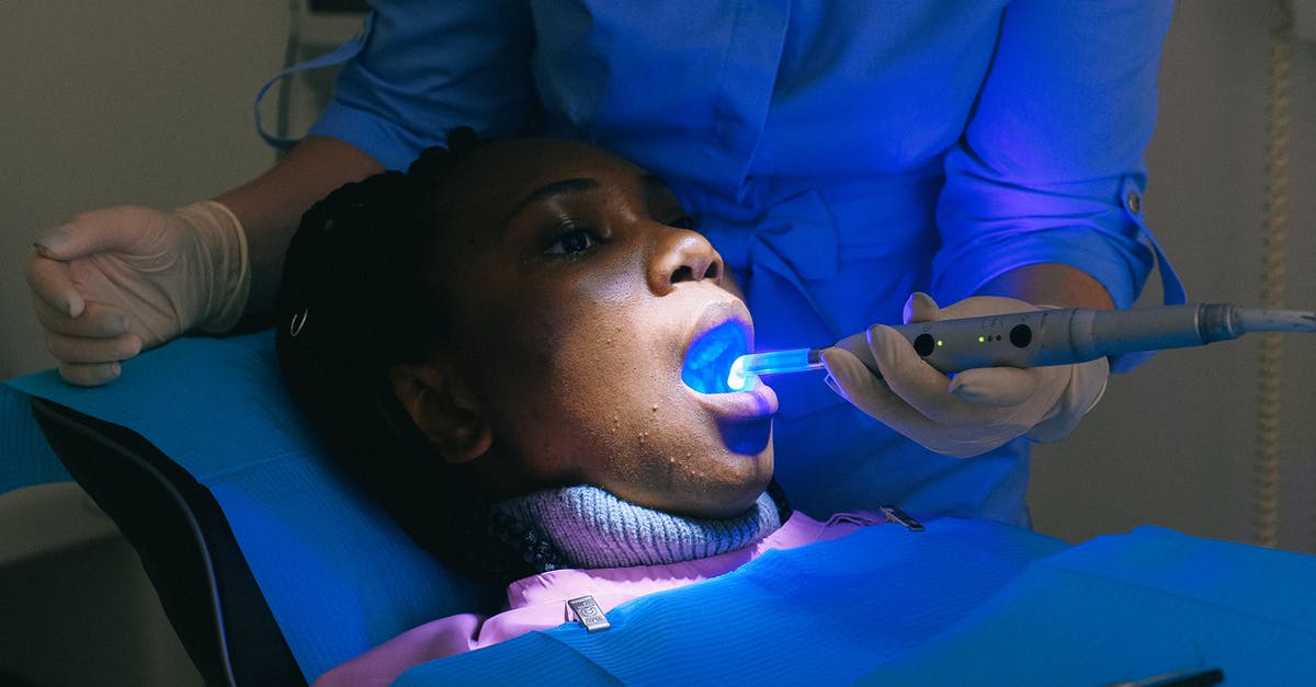 Electronic medical devices through British airport security - African American woman sitting in dental chair and receiving treatment with curing light from crop doctor Electronic medical devices through British airport security - African American woman sitting in dental chair and receiving treatment with curing light from crop doctor