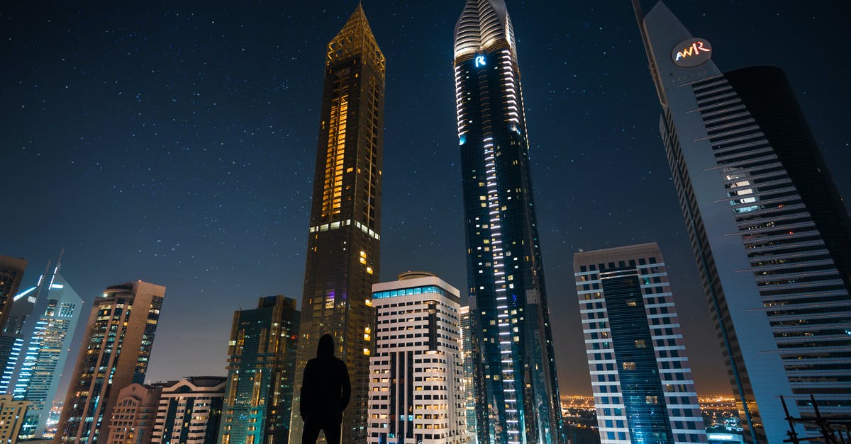 Emirates Dubai Connect - which hotel? - Man Standing in Assorted Building String Light during Night Time Emirates Dubai Connect - which hotel? - Man Standing in Assorted Building String Light during Night Time