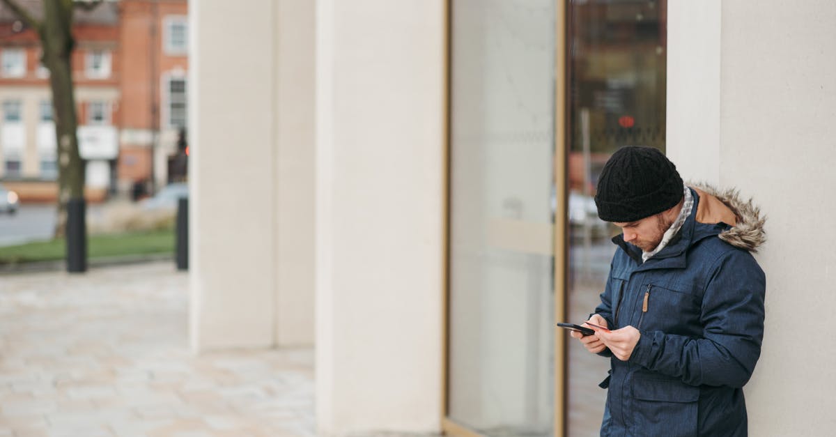 Enter EU Schengen Area on a Type D Visa [duplicate] - Concentrated man in warm outwear standing on city street near building and browsing smartphone in daytime