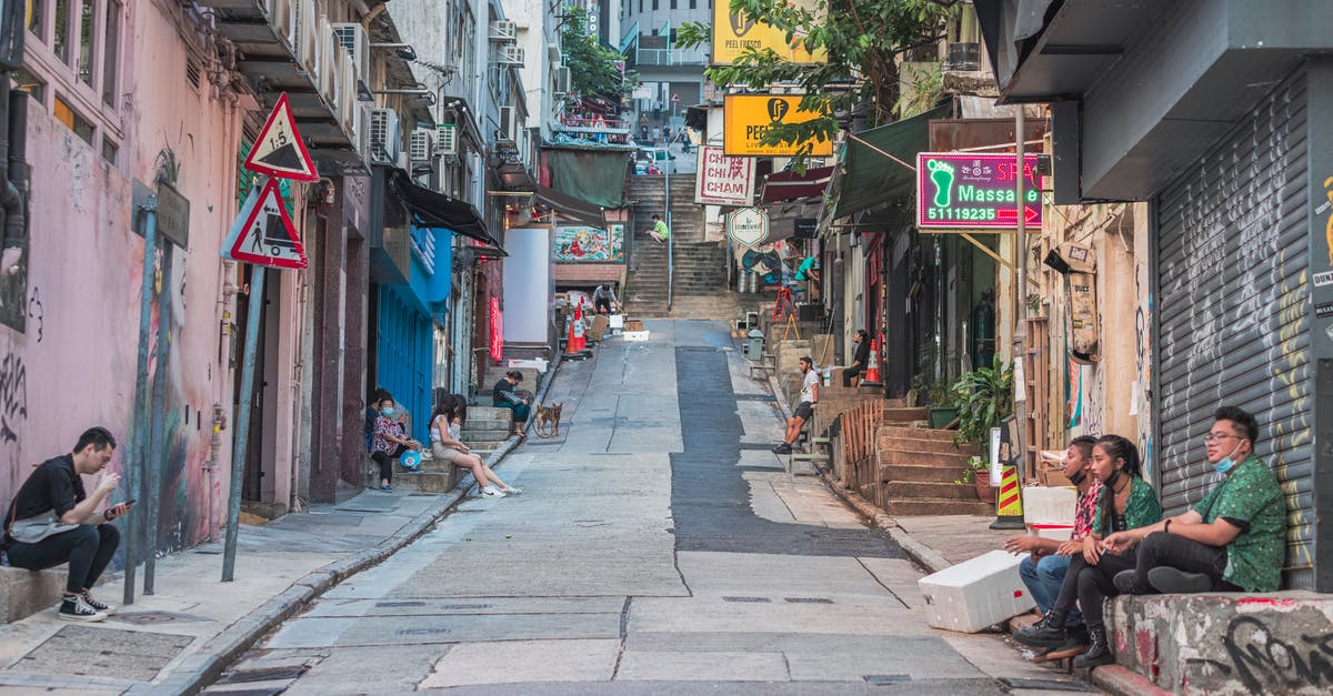 Entering China from Hong Kong without a Hong Kong visa - Man in Black Jacket Sitting on Brown Wooden Bench Near Store Entering China from Hong Kong without a Hong Kong visa - Man in Black Jacket Sitting on Brown Wooden Bench Near Store