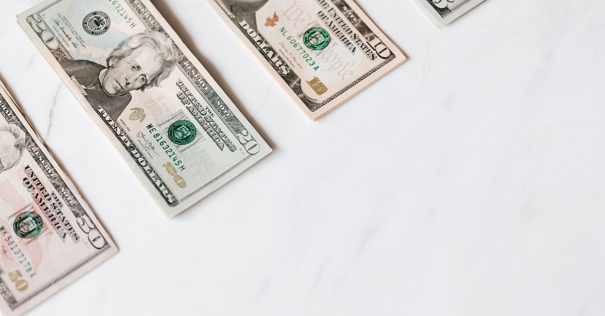 Entering the US twice on different passports - Set of various dollar banknotes on white table Entering the US twice on different passports - Set of various dollar banknotes on white table