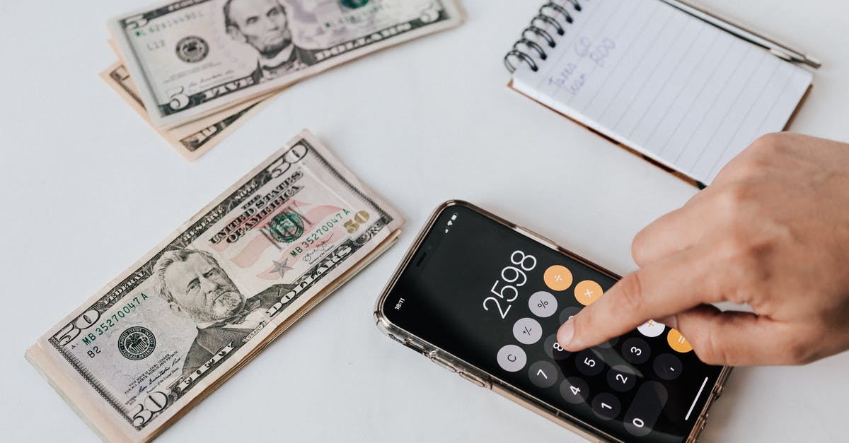 Entering using American passport and leaving using Polish Passport - From above of crop anonymous economist calculating total amount of income using calculator app on cellphone near piles of greenbacks and notebook with pen