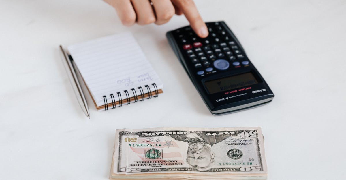 Entering using American passport and leaving using Polish Passport - Top view of crop faceless economist touching calculator button while counting income near heap of paper bills and small notebook with pen