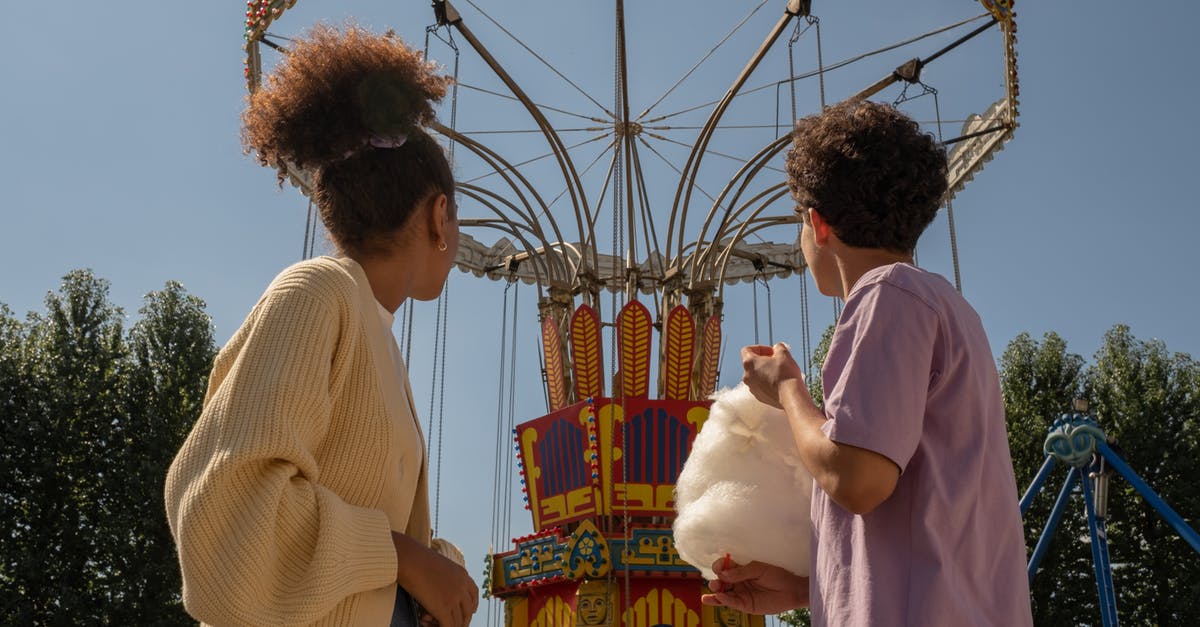 ESTA 90 day start date - Teenage couple on date in amusement park looking at big carousel ESTA 90 day start date - Teenage couple on date in amusement park looking at big carousel