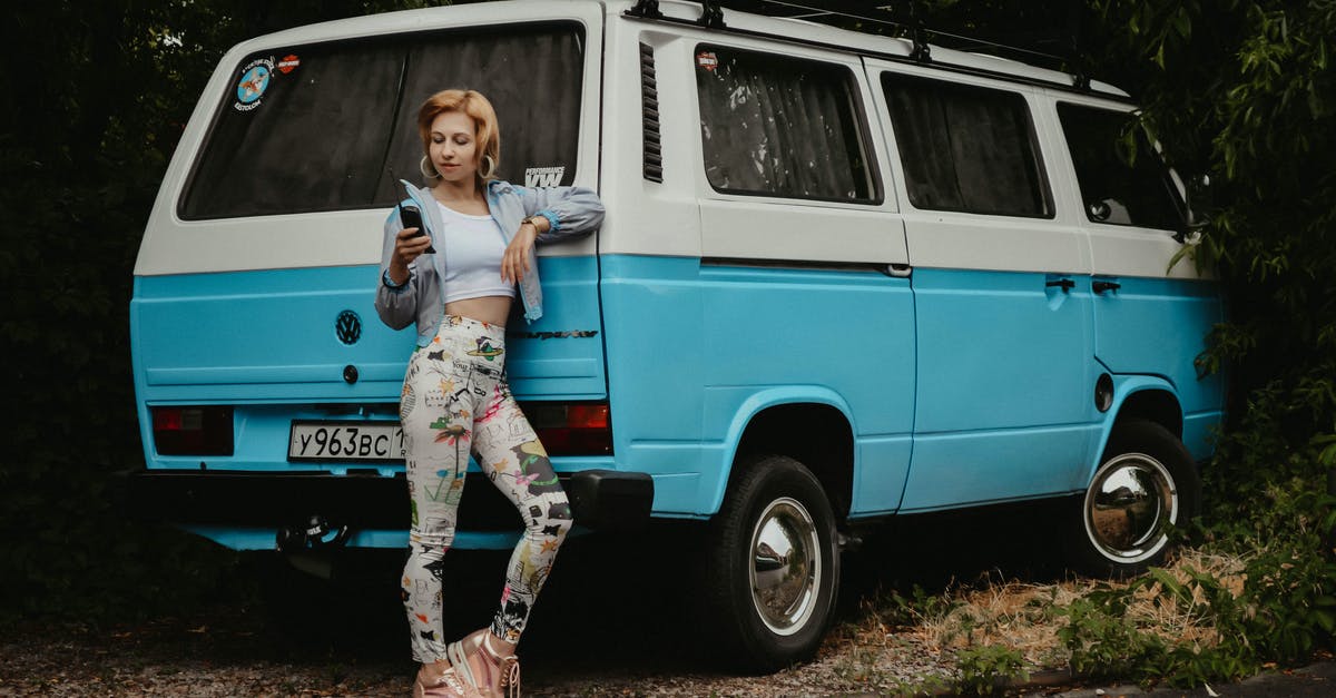 EU Roaming rules: call from abroad to foreign number - Full length of young female in vintage outfit dialing number on wireless handset while standing near minivan EU Roaming rules: call from abroad to foreign number - Full length of young female in vintage outfit dialing number on wireless handset while standing near minivan