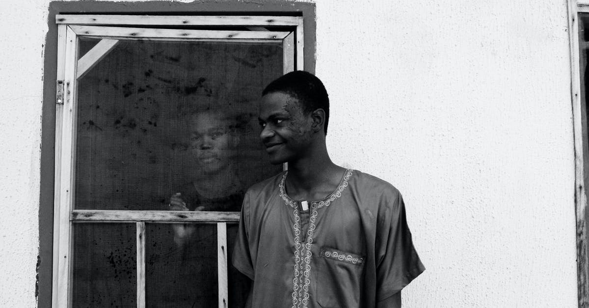 EU roaming when calling a number outside the EU? - Black and white of slim happy African American guy looking away while standing near house with concrete walls and old window with serious partner inside building EU roaming when calling a number outside the EU? - Black and white of slim happy African American guy looking away while standing near house with concrete walls and old window with serious partner inside building