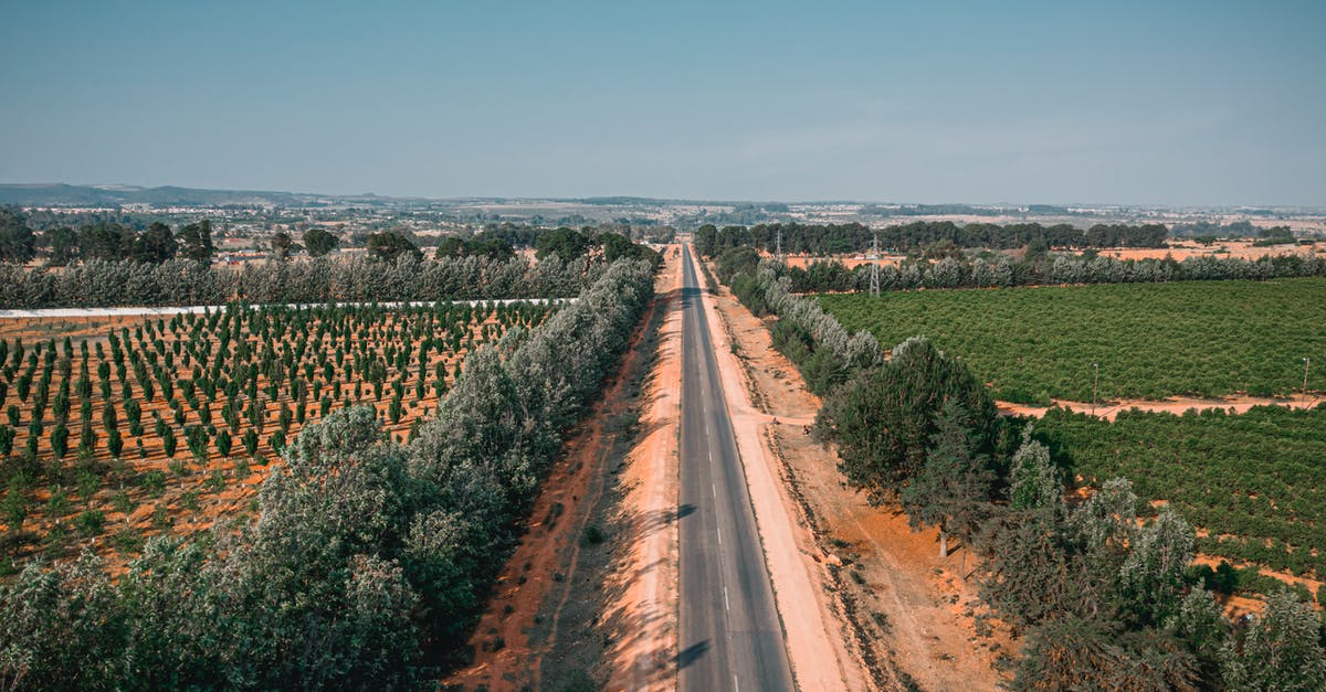 Europe: differences between colours of highway road-signs - Aerial Shot of a Road Between Farm Lands Europe: differences between colours of highway road-signs - Aerial Shot of a Road Between Farm Lands