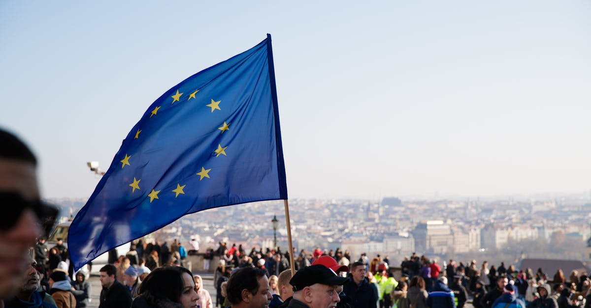 European citizen visiting Cuba while in US? - Crowd of people walking on street with waving flag of European Union Courtesy during protest in city against residential buildings European citizen visiting Cuba while in US? - Crowd of people walking on street with waving flag of European Union Courtesy during protest in city against residential buildings