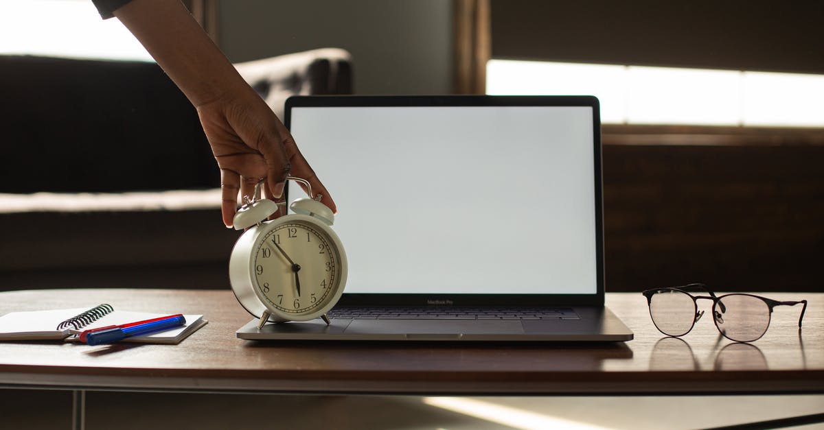 Eurostar delay compensation for journeys with connections - Anonymous black person touching alarm clock near opened netbook with white blank screen placed on table with notebook and pens Eurostar delay compensation for journeys with connections - Anonymous black person touching alarm clock near opened netbook with white blank screen placed on table with notebook and pens