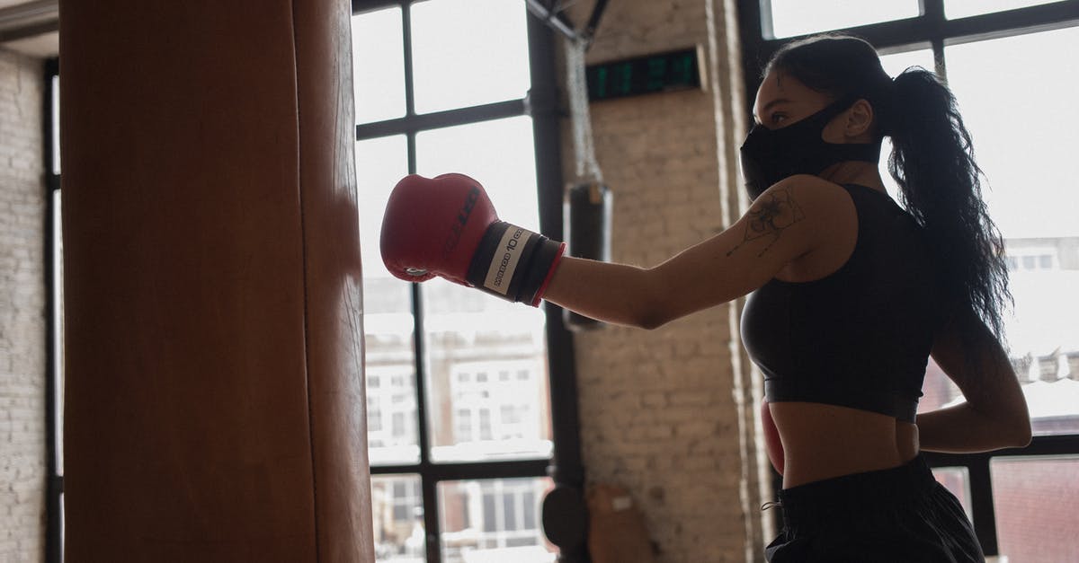 Eurostar train to Paris during a strike - Tattooed black boxer in face mask punching heavy bag indoors Eurostar train to Paris during a strike - Tattooed black boxer in face mask punching heavy bag indoors
