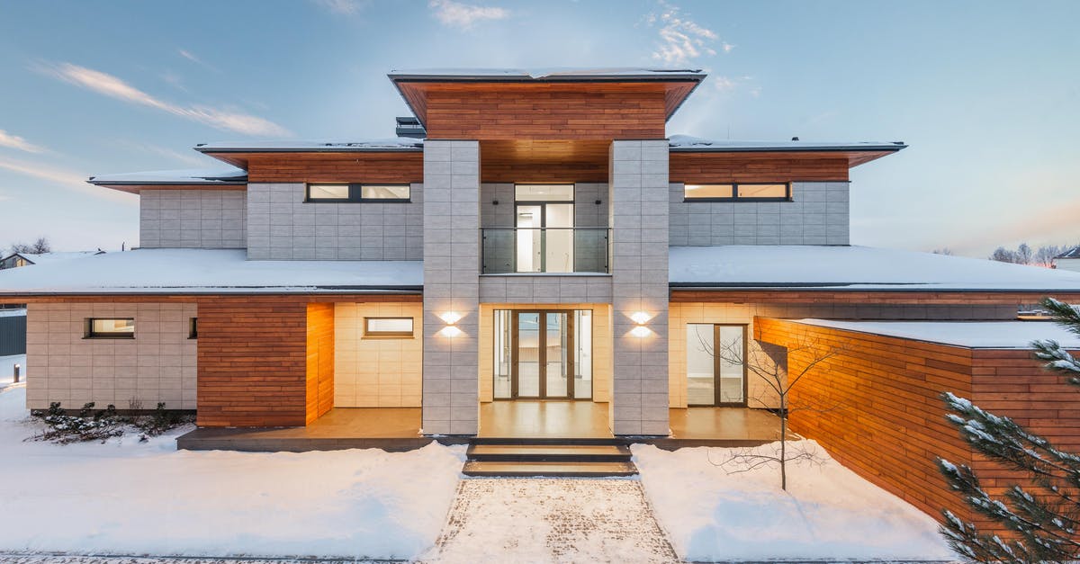 Existing ESTA after new citizenship? - Backyard view of new modern luxurious cottage house with stone and wooden facade and illumination in winter countryside Existing ESTA after new citizenship? - Backyard view of new modern luxurious cottage house with stone and wooden facade and illumination in winter countryside