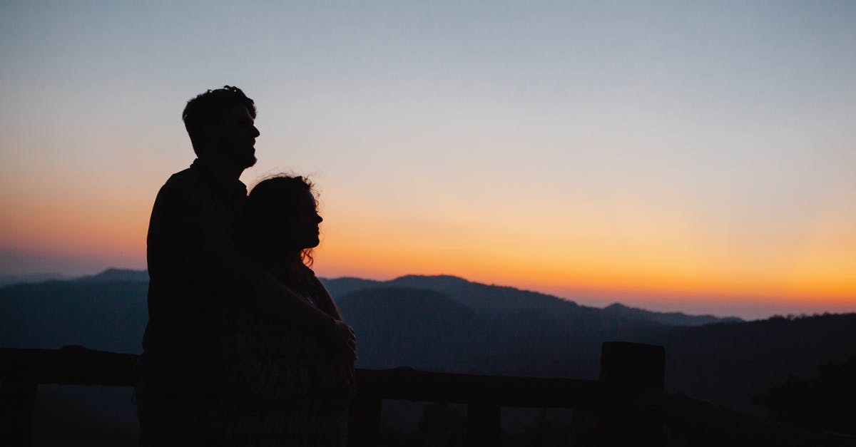 Exit stamp date not clear; problematic for future? - Side view of anonymous couple hugging near rough rocky mountains under clear cloudless sunset Exit stamp date not clear; problematic for future? - Side view of anonymous couple hugging near rough rocky mountains under clear cloudless sunset
