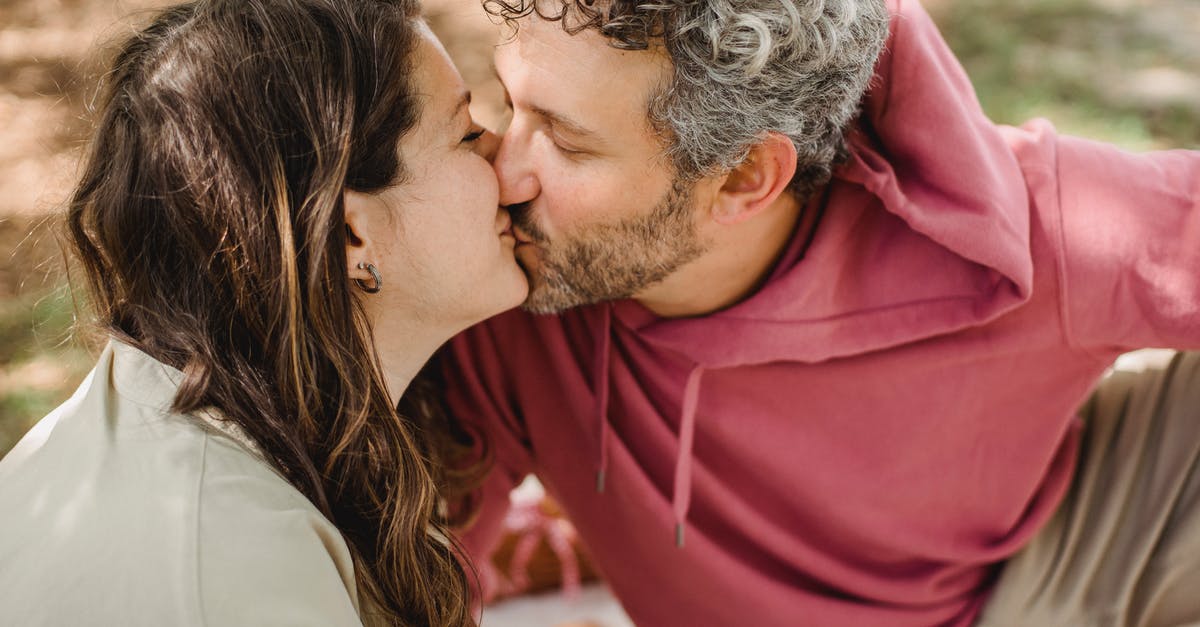 Expected arrival date changed - Australian Visitor 600 Visa - Side view of romantic wife and husband kissing each other while sitting on blanket on blurred background during picnic in nature Expected arrival date changed - Australian Visitor 600 Visa - Side view of romantic wife and husband kissing each other while sitting on blanket on blurred background during picnic in nature