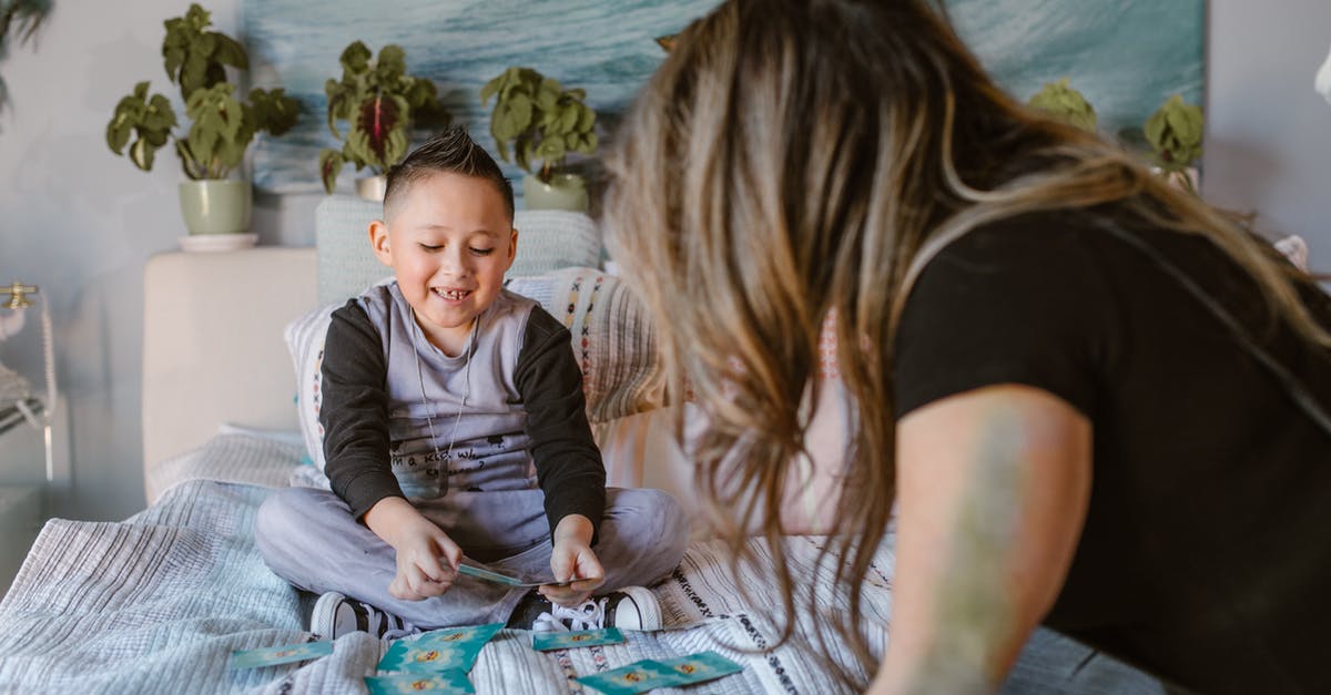 Expenditure in Poland - Forex Card doesn't have Złoty - Cheerful kid playing cards game with unrecognizable mom on bed Expenditure in Poland - Forex Card doesn't have Złoty - Cheerful kid playing cards game with unrecognizable mom on bed