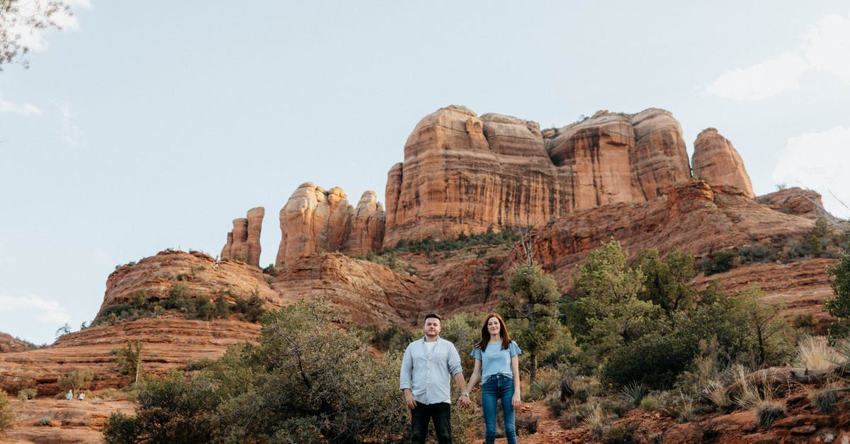 Extending visitor stay in the US - Man and Woman Standing on Brown Rock Formation Extending visitor stay in the US - Man and Woman Standing on Brown Rock Formation
