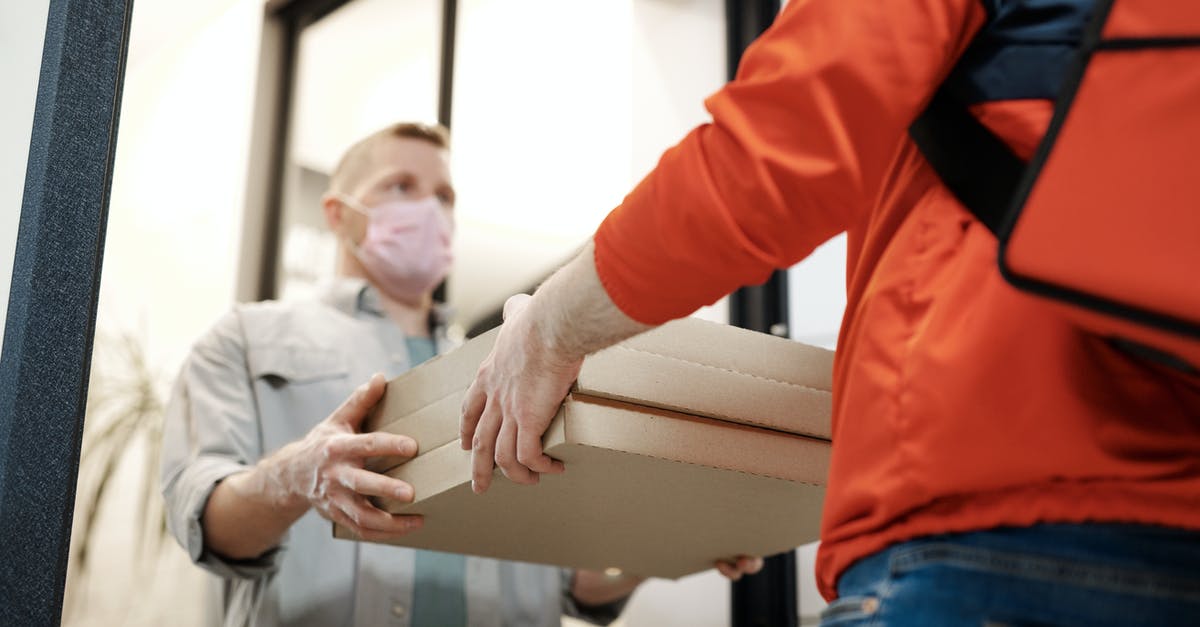Extension of stay at USA due to COVID-19 lockdown - Man Wearing a Face Mask Receiving a Pizza Delivery Extension of stay at USA due to COVID-19 lockdown - Man Wearing a Face Mask Receiving a Pizza Delivery