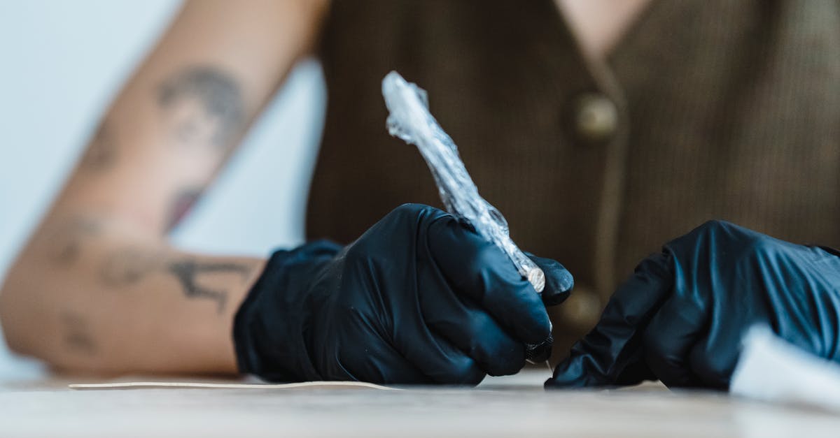 Fake work permit and deportation - Crop anonymous artist in black gloves drawing with tattoo machine on practice skin on blurred background Fake work permit and deportation - Crop anonymous artist in black gloves drawing with tattoo machine on practice skin on blurred background