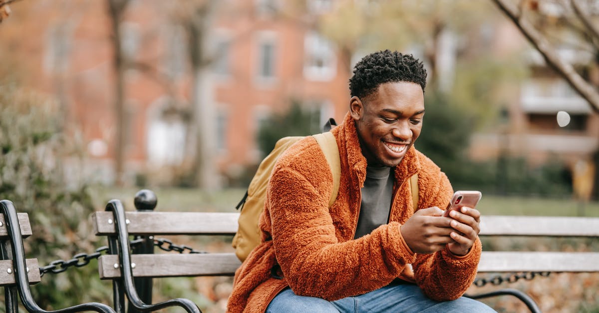 Fall asleep in terminal and miss connection fight: recover change fee - Delightful African American man surfing modern cellphone in city park Fall asleep in terminal and miss connection fight: recover change fee - Delightful African American man surfing modern cellphone in city park
