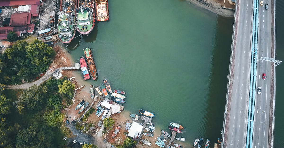 Fastest way to reach St-Jean-Pied-de-Port from Barcelona or other Spanish airports - Drone view of cars riding on bridge over channel near various moored boats in tropical countryside Fastest way to reach St-Jean-Pied-de-Port from Barcelona or other Spanish airports - Drone view of cars riding on bridge over channel near various moored boats in tropical countryside