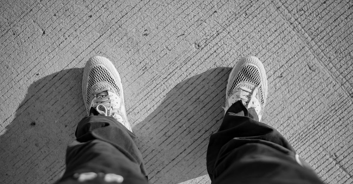Fastest way to reach St-Jean-Pied-de-Port from Barcelona or other Spanish airports - Black and white of from above of crop unrecognizable male in casual clothes and sneakers standing on asphalt roadway in sunny day Fastest way to reach St-Jean-Pied-de-Port from Barcelona or other Spanish airports - Black and white of from above of crop unrecognizable male in casual clothes and sneakers standing on asphalt roadway in sunny day