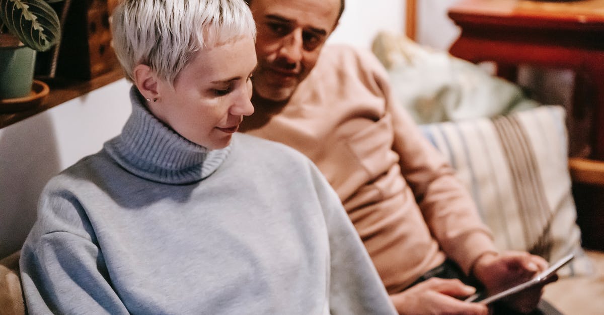 Filipina married to British wanting to live in Spain.Difficulty in applying Schengen Visa for a start [closed] - Calm female with short hair in stylish sweater sitting on sofa near ethnic adult husband using tablet during weekend at home