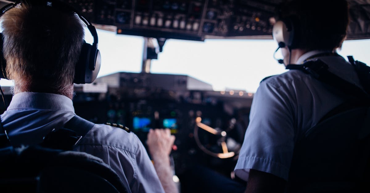 Flight flown + operated by completely different, non-code-share airline? - Back view of anonymous male pilots in uniform and headset navigating modern airplane while taking off Flight flown + operated by completely different, non-code-share airline? - Back view of anonymous male pilots in uniform and headset navigating modern airplane while taking off