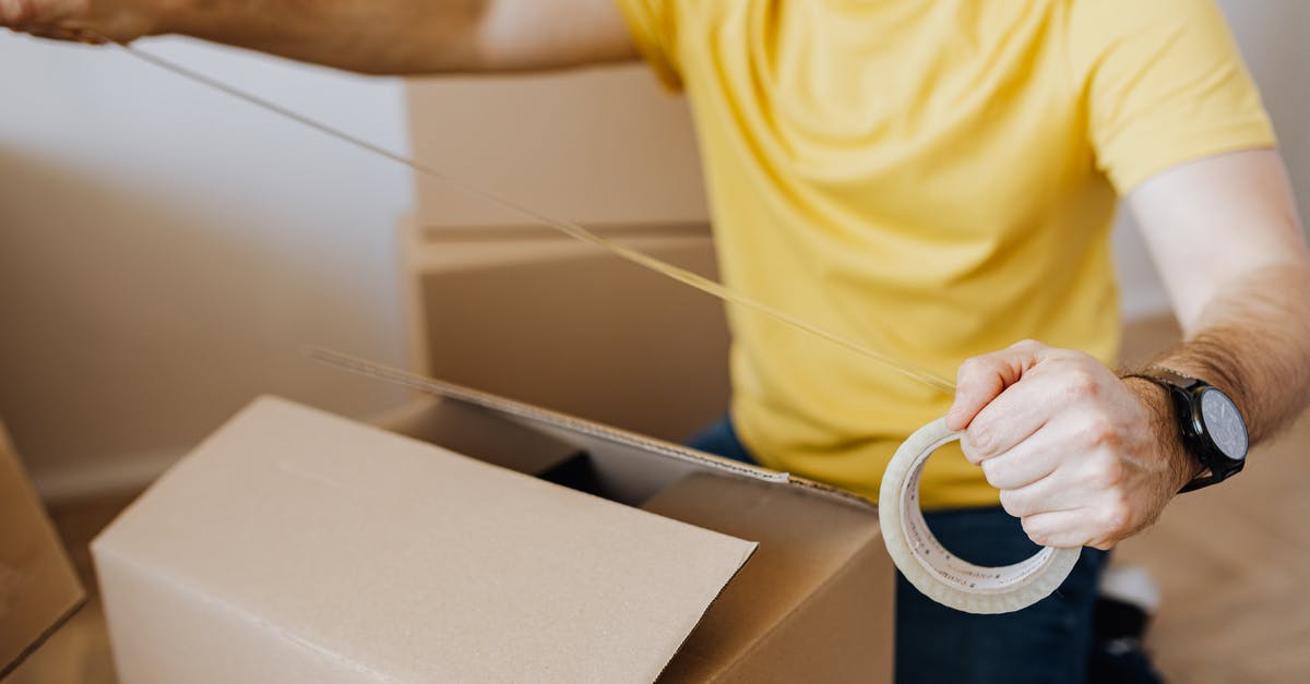 Flight itinerary/time/date change - Crop man with cardboard boxes while packing belongings Flight itinerary/time/date change - Crop man with cardboard boxes while packing belongings