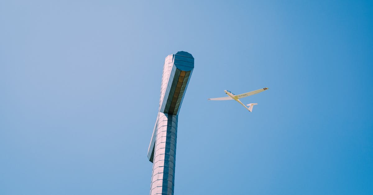 Flight/Train combo from Europe to Toronto/Vancouver - From below of high metal Nivolet Cross with plane flying over cloudless blue sky in France Flight/Train combo from Europe to Toronto/Vancouver - From below of high metal Nivolet Cross with plane flying over cloudless blue sky in France