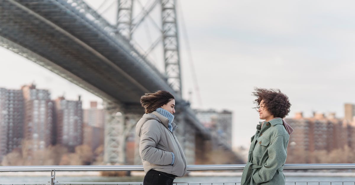 Flying stand by from US to Europe -- is it still worth it, and if so, how to do it? - Side view young female friends in warm clothes having conversation and standing face to face on New York City embankment on cold winter day
