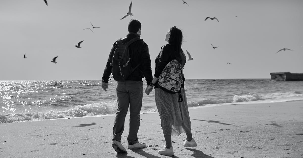 Flying to Daughter's College Town, Flying Back Together: Booking Roundtrip and One-way - Man and Woman Walking on Beach While Holding Hands Flying to Daughter's College Town, Flying Back Together: Booking Roundtrip and One-way - Man and Woman Walking on Beach While Holding Hands