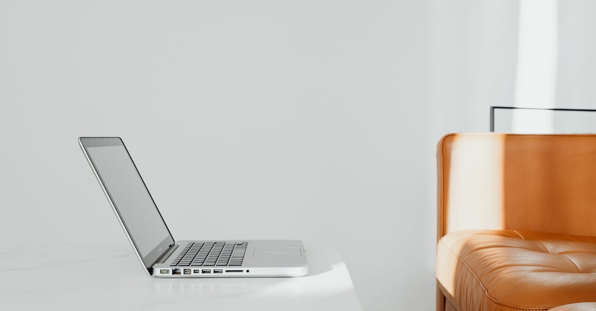 Flying With Uncharged Laptop - Silver Macbook on White Table Flying With Uncharged Laptop - Silver Macbook on White Table