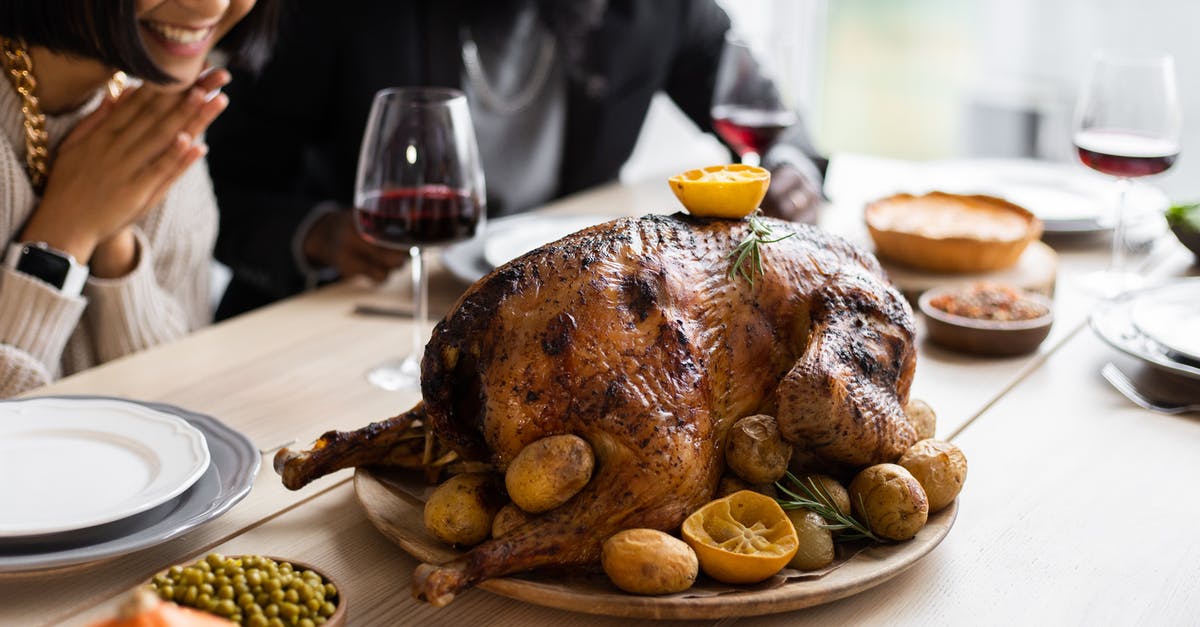 Food imports and exports from Turkey - Cheerful multiethnic couple sitting at table with roasted turkey Food imports and exports from Turkey - Cheerful multiethnic couple sitting at table with roasted turkey