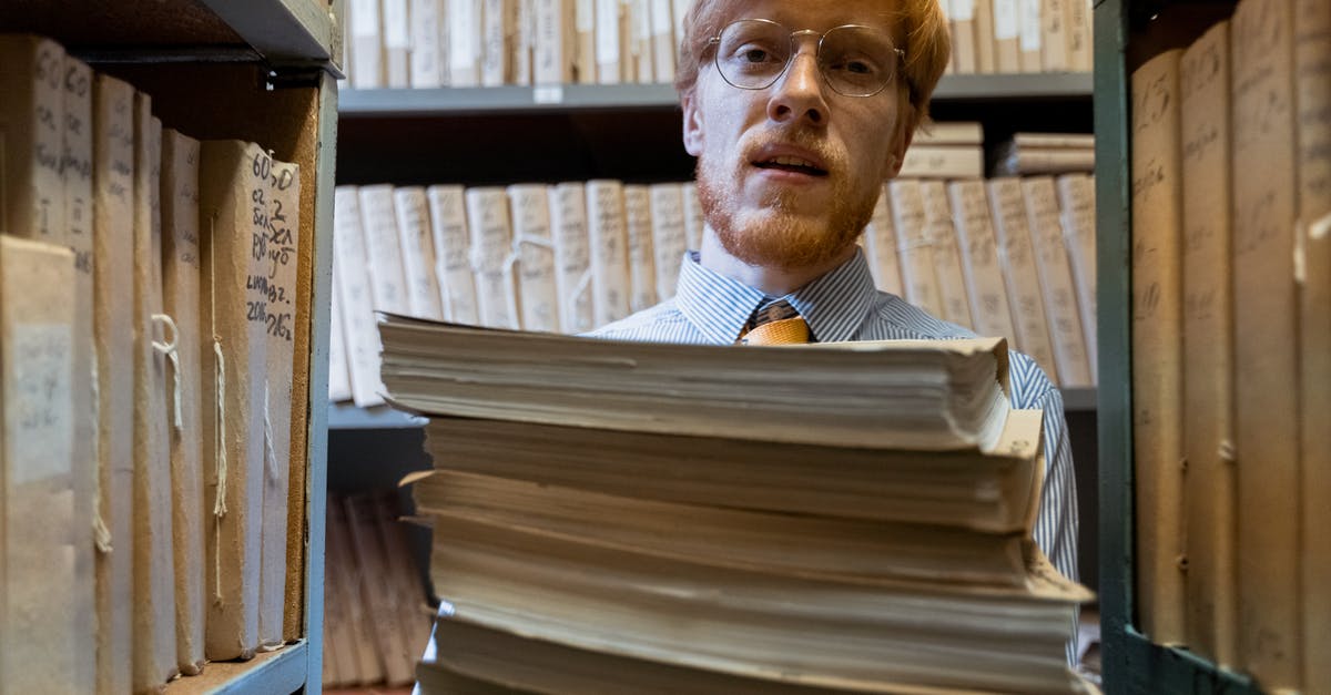 Foreign storage of a carry-on - A Man Carrying a Pile of Documents Foreign storage of a carry-on - A Man Carrying a Pile of Documents