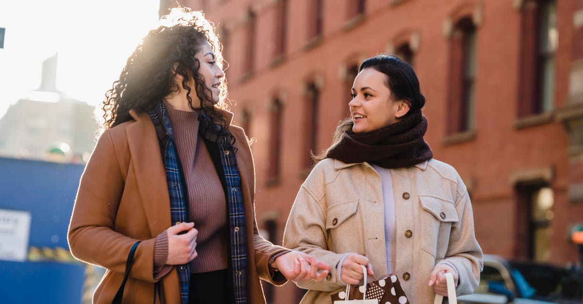 Foreigner borrowing a car from a friend in the UK. Insurance? - Low angle of positive female friends talking to each other while carrying paper packets after shopping together