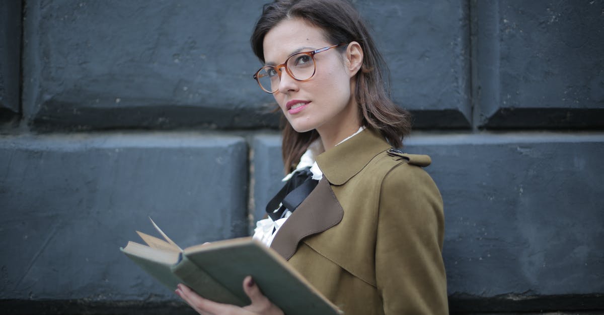 Forgot old passport with schengen/student visa - From below confident young female in glasses and elegant vintage clothes looking away and contemplating while reading rook on street near black wall of aged building in city Forgot old passport with schengen/student visa - From below confident young female in glasses and elegant vintage clothes looking away and contemplating while reading rook on street near black wall of aged building in city