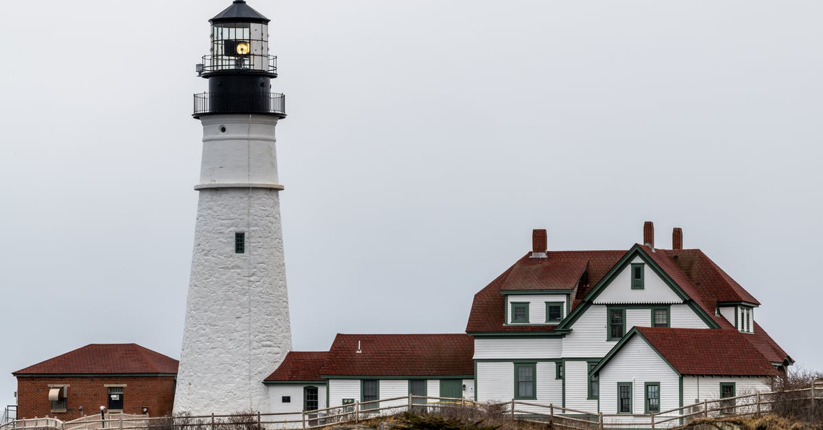 Freighter travel from the east coast of the U.S. to Copenhagen [closed] - White lighthouse and aged residential houses against cloudy sky