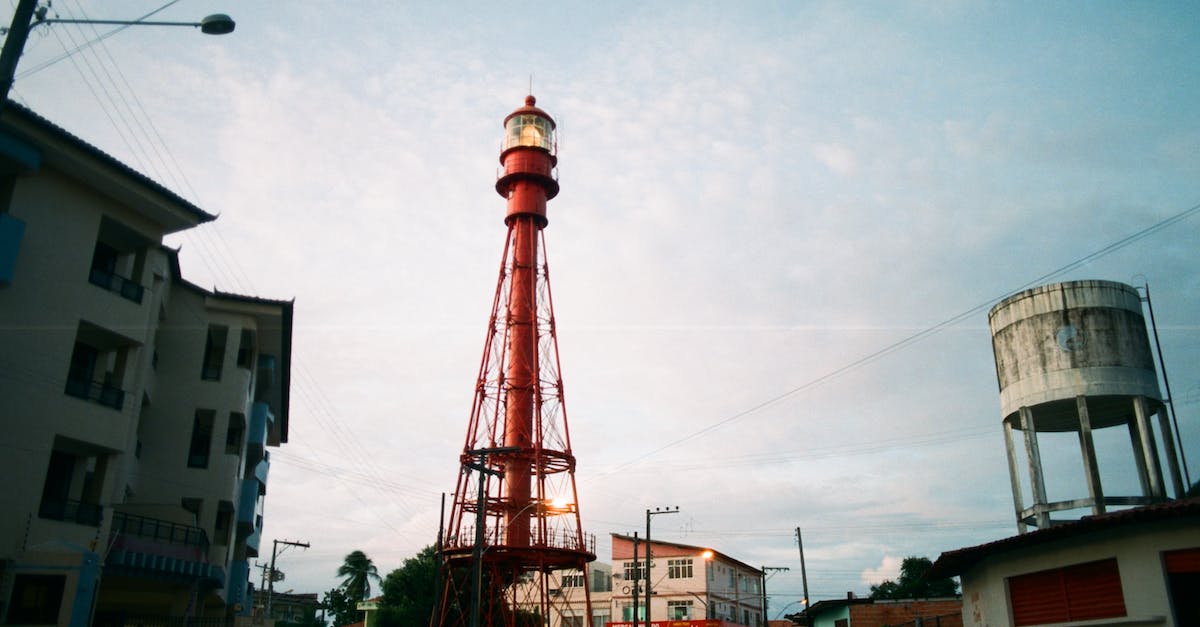 From Tallinn harbour to the main bus station - From below of red metal tower of lighthouse in urban dock with industrial buildings around From Tallinn harbour to the main bus station - From below of red metal tower of lighthouse in urban dock with industrial buildings around