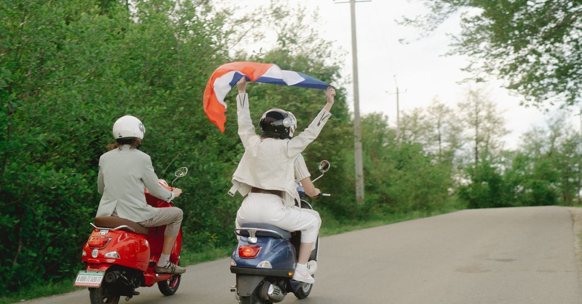 Getting a motorcycle license in France - People Riding a Motor Scooters on the Road while Holding a Flag Getting a motorcycle license in France - People Riding a Motor Scooters on the Road while Holding a Flag