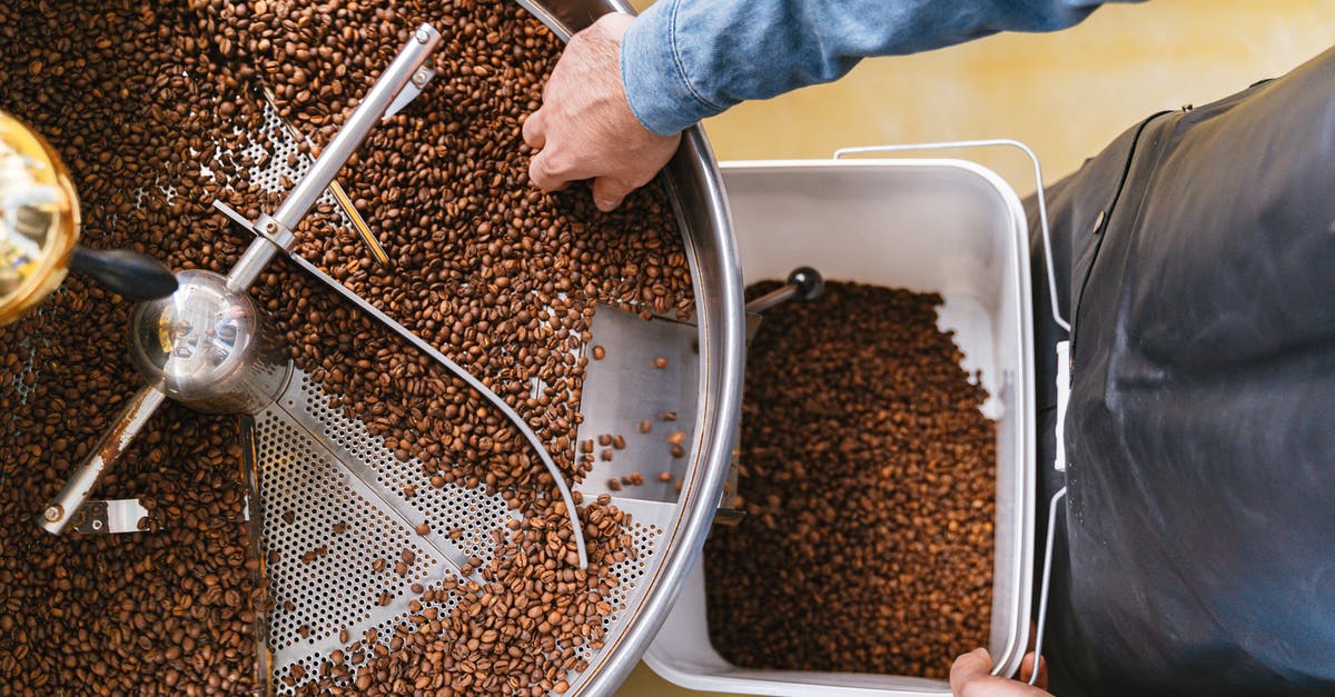 Getting around the Cotswolds from Cheltenham - A Person Holding a Bucket while Getting Coffee Beans From the Machine Getting around the Cotswolds from Cheltenham - A Person Holding a Bucket while Getting Coffee Beans From the Machine