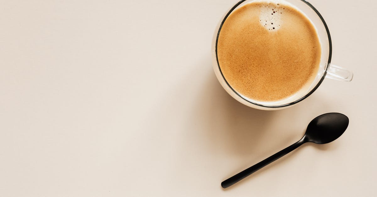 Getting Dutch Schengen visa from the Italian embassy - Top view of glass of aromatic light brown coffee with foam and small bubbles on top near metal spoon on beige surface Getting Dutch Schengen visa from the Italian embassy - Top view of glass of aromatic light brown coffee with foam and small bubbles on top near metal spoon on beige surface