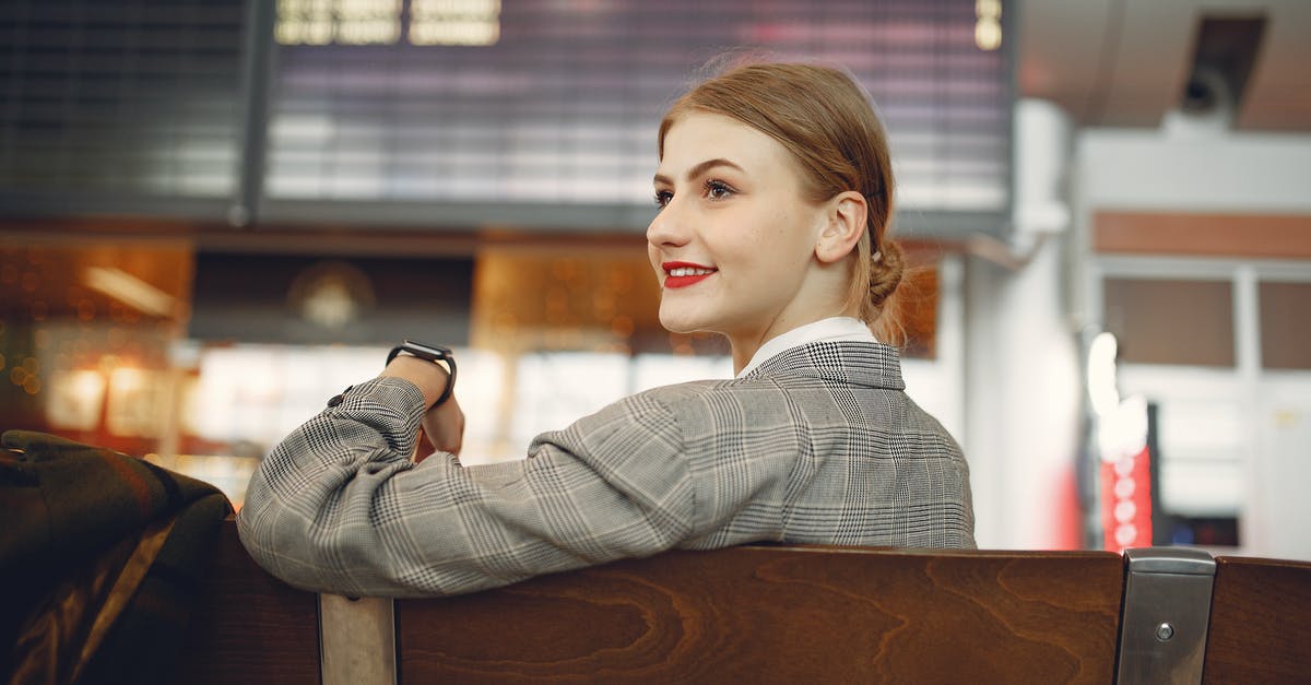 Getting from San Francisco (Union Square) to Oakland Airport by public transport - Side view of positive female manager waiting for flight on wooden seat in airport
