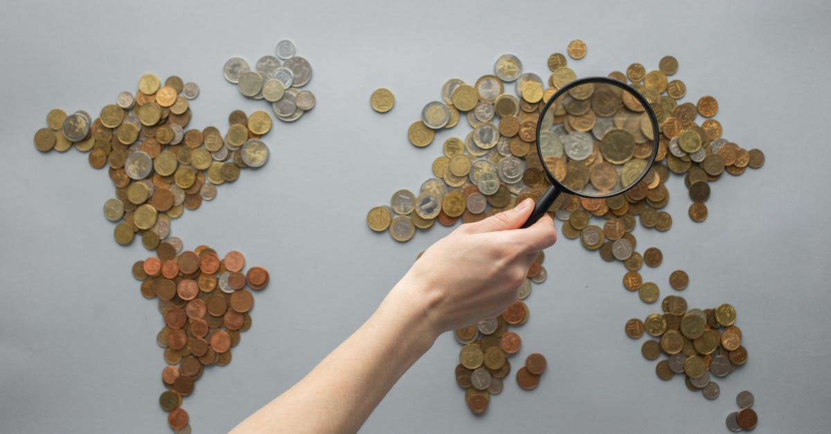 Getting into Brazil with an onward ticket from another country - Top view of crop unrecognizable traveler with magnifying glass standing over world map made of various coins on gray background Getting into Brazil with an onward ticket from another country - Top view of crop unrecognizable traveler with magnifying glass standing over world map made of various coins on gray background