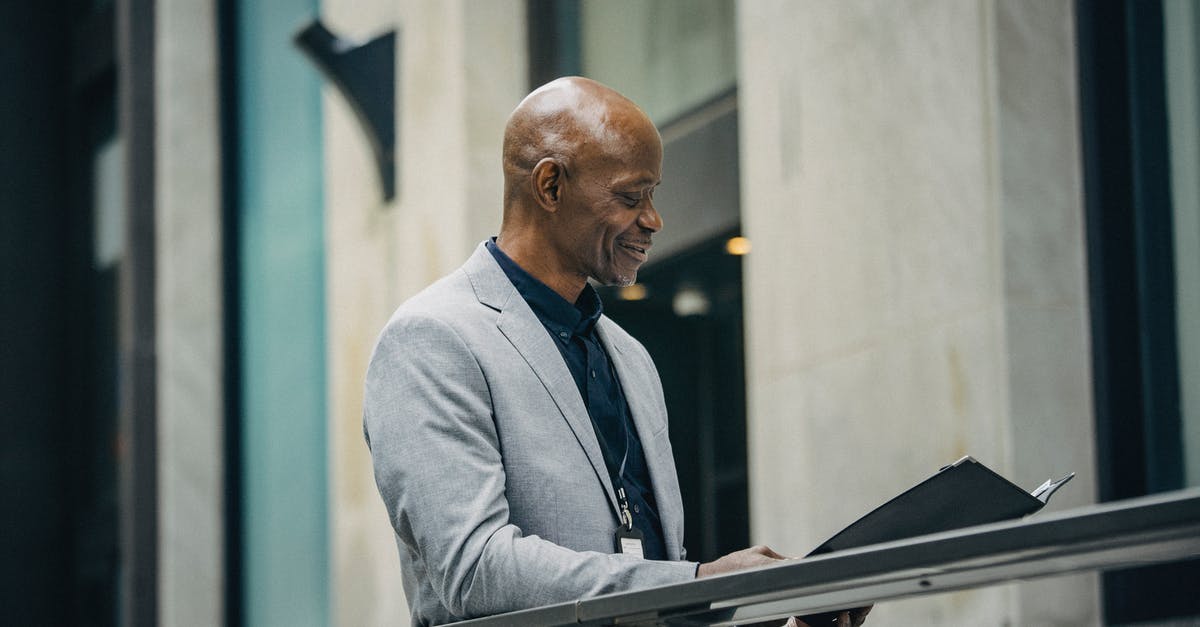 go to check-in for visa check and boarding card - Cheerful African American manager reading documents in folder go to check-in for visa check and boarding card - Cheerful African American manager reading documents in folder