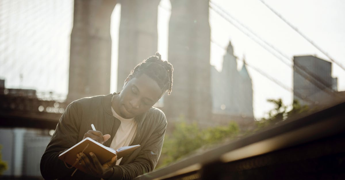 Got refused for a UK visa. Think they might have incorrectly interpreted bank statements - Low angle of concentrated young African American male journalist writing thoughts in notepad while chilling on city riverbank on sunny day