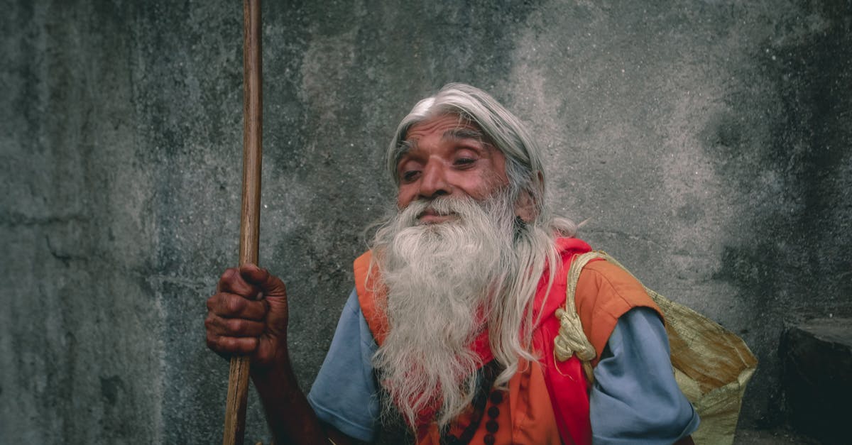 Halifax long layover, recheck bags? - Poor senior Indian man with gray beard against rough wall