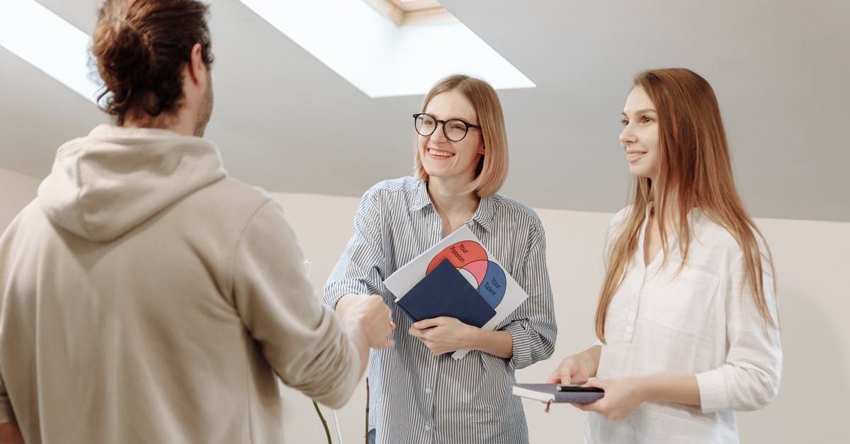 Handshake while holding own right elbow - Women Holding Notebooks Talking to a Man in Hoodie Handshake while holding own right elbow - Women Holding Notebooks Talking to a Man in Hoodie