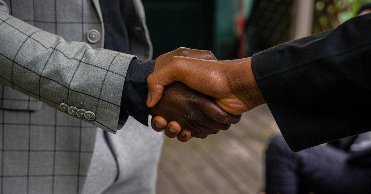 Handshake while holding own right elbow - Men in Suit Jackets Shaking Hands Handshake while holding own right elbow - Men in Suit Jackets Shaking Hands