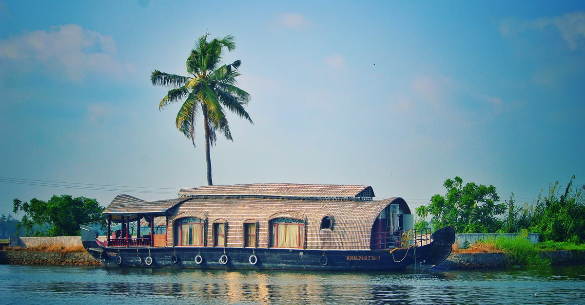 Have hotels been re-established in Kedarnath, India after the floods? - Picturesque view of river with green palms on bank and shabby wooden boathouse under blue sky in tropical countryside